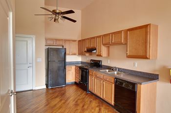 A kitchen with wooden cabinets and a black refrigerator. at Nantucket Lofts Apartments, Kinston